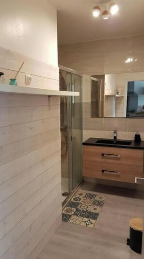Enjoy a refreshing shower in the sleek bathroom with a glass-enclosed shower area and a separate sink.
