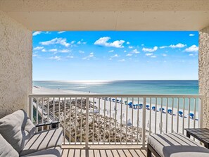 A balcony with a view of a beach, white railing, and a few beach chairs. - 501- Completely Renovated 5th Floor End Unit, W/ Free Bch Svc (Destin)