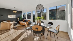 Un salon moderne avec un coin repas, de grandes fenêtres et un plafond noir.