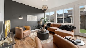 Un salon moderne avec un mur foncé, une grande fenêtre et un luminaire au plafond.