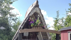 Eine kleine Holzhütte mit geneigtem Dach, einer Holztür und einem kleinen Fenster.