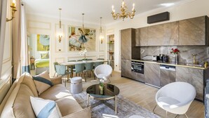 A modern living room with a sofa, chairs, a coffee table, and a dining area. - Merveil - Signature Suite - Louvre - Opera I (Paris)