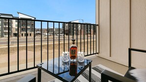 A balcony with a table, two glasses, and a bottle of Old Elk whiskey. - Urban Oasis near Breweries & Old Town - Free Bikes (Fort Collins)