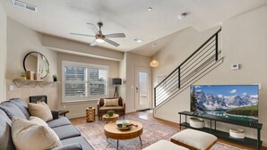 A spacious living room with a gray sofa, a round wooden coffee table, and a large flat-screen TV on a black stand. - Urban Oasis near Breweries & Old Town - Free Bikes (Fort Collins)