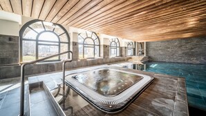 A modern indoor pool area with a wooden ceiling, stone walls, and a glass-enclosed hot tub. - Le Gui- Lovely ground floor apartment in Chamonix (Chamonix)