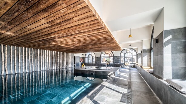 A modern indoor swimming pool with a wooden ceiling, stone walls, and large windows. - Le Gui- Lovely ground floor apartment in Chamonix (Chamonix)