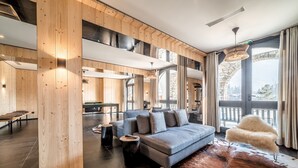 A modern living room with a grey sofa, wooden accents, a cowhide rug, and a stone arch window. - Le Gui- Lovely ground floor apartment in Chamonix (Chamonix)
