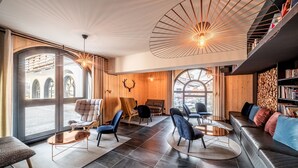 A modern interior with a large window, a leather sofa, and a wooden wall with a deer head decoration. - Le Gui- Lovely ground floor apartment in Chamonix (Chamonix)