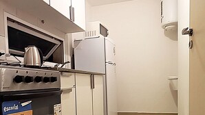 Et lille køkken med hvide skabe, en komfur, en mikrobølgeovn og et køleskab.