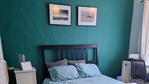 Ein Schlafzimmer mit Bett, Nachttisch, Schreibtisch und zwei gerahmten Bildern an der Wand.