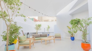 A modern outdoor seating area with a sofa, chairs, and tables, surrounded by potted plants. - StayHere Rabat - Agdal Quiet Living (Rabat)