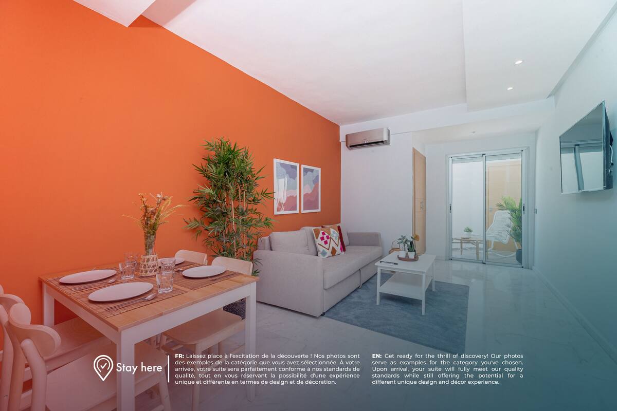 Uma sala de estar moderna com área de jantar, com um sofá, uma mesa de centro e uma mesa de jantar posta para dois.