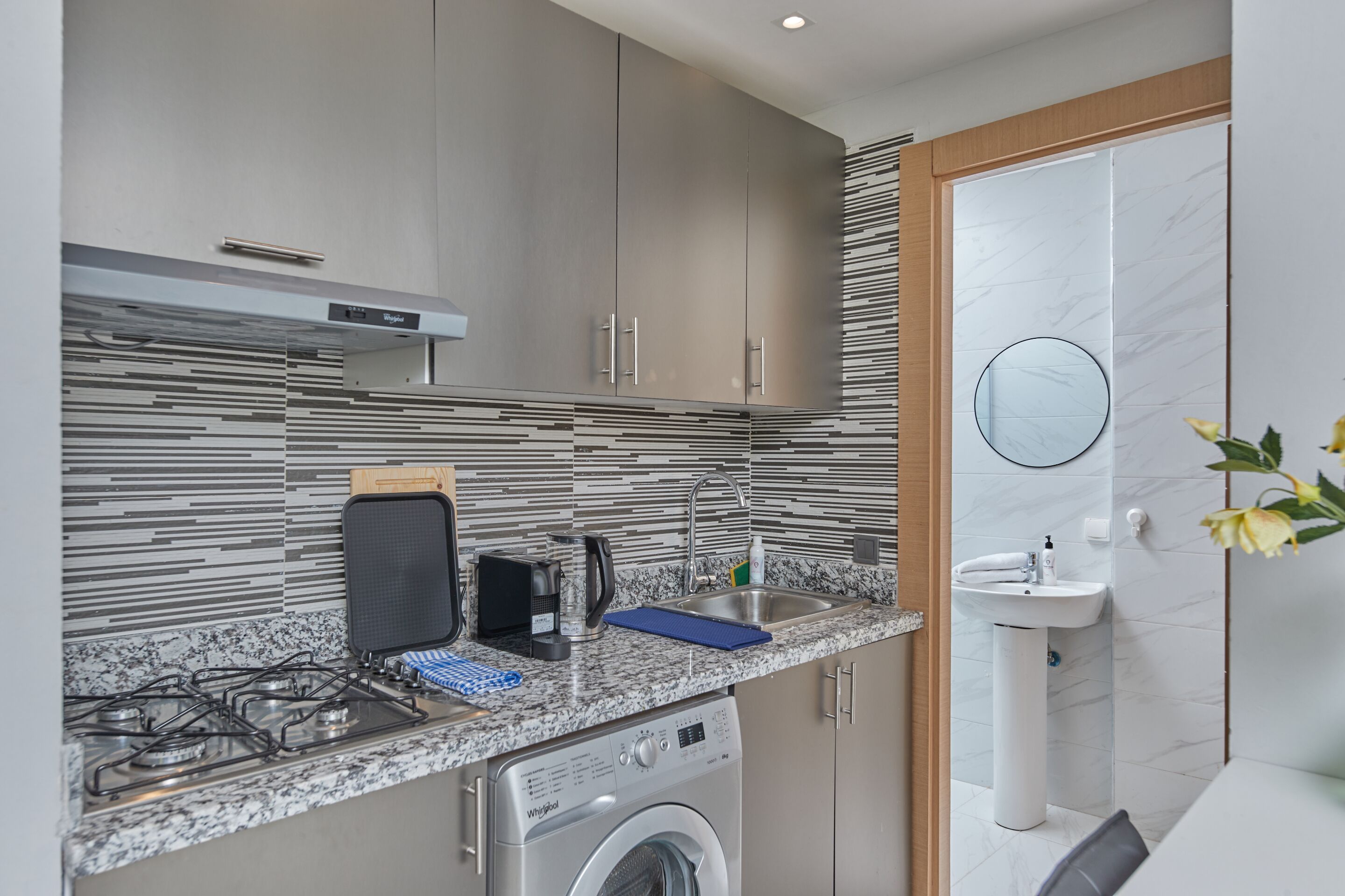 Una cocina compacta con lavadora integrada, un lavabo y una estufa.