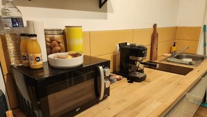 A kitchen with a black microwave, coffee maker, and a wooden countertop. - Sous les Toits de Béthune (Béthune)