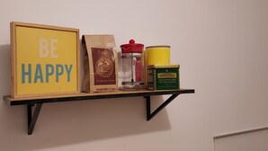 A shelf with a framed sign saying "BE HAPPY," a bag of coffee, a glass container, and a canister. - Sous les Toits de Béthune (Béthune)
