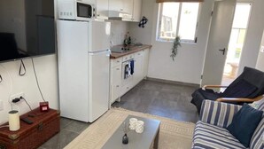 A compact living space with a kitchenette, a sofa, a coffee table, and a television mounted on the wall. - Cosy 1 bed pool house (L'Alfàs del Pi)