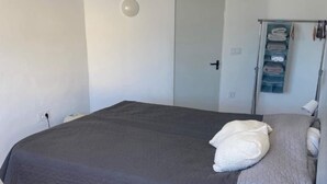 A bedroom with a bed, a bedside table with a lamp, a wardrobe, and a towel rack. - Cosy 1 bed pool house (L'Alfàs del Pi)