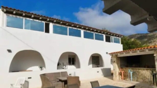 A white building with a tiled roof, outdoor seating area with tables and chairs, and a covered patio. - Cosy 1 bed pool house (L'Alfàs del Pi)