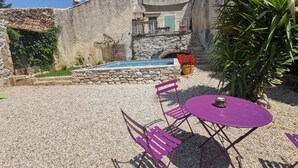 A patio with a pool, stone walls, and a table with chairs. - 3 bedroom house, private pool, 10min from Pont du Gard (Meynes)