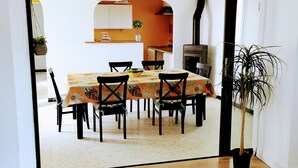A dining area with a wooden table and chairs, a hanging light fixture, and a potted plant. - 3 bedroom house, private pool, 10min from Pont du Gard (Meynes)