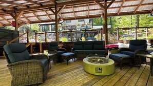 An outdoor patio with wicker furniture, a round table, and a view of a garden with plants and a building in the background. - Close to city, far from ordinary. 
Peace and tranquility await! (Westerville)