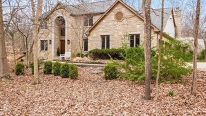 A stone house with a stone chimney, a porch with a chair, and a leaf-covered ground. - Close to city, far from ordinary. 
Peace and tranquility await! (Westerville)