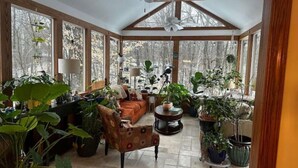 A sunroom with a high ceiling, large windows, and a variety of potted plants. - Close to city, far from ordinary. 
Peace and tranquility await! (Westerville)