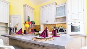 Una cocina con armarios blancos, encimera de granito y comedor con mesa para cuatro.