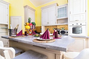 A kitchen with white cabinets, a granite countertop, and a microwave. - Golden Brilliance Suite (Hlavní mesto Praha)