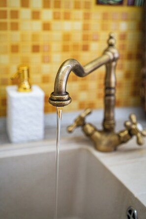 A bathroom sink with a running faucet and a gold-colored faucet handle. - Golden Brilliance Suite (Hlavní mesto Praha)