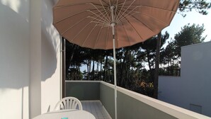 Ein Balkon mit Tisch, Stühlen und Sonnenschirm.