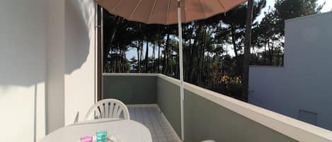 A balcony with a table, chairs, and an umbrella.