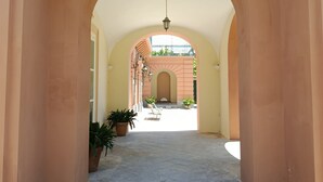 Un pasillo con arcos, plantas en macetas y una vista de un edificio al fondo.