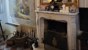 Un salón espacioso con chimenea, un espejo grande y un cuadro decorativo en la pared.
