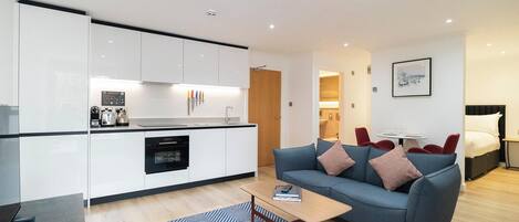 A modern living room with a sofa, a coffee table, and a dining area with a small table and chairs.
