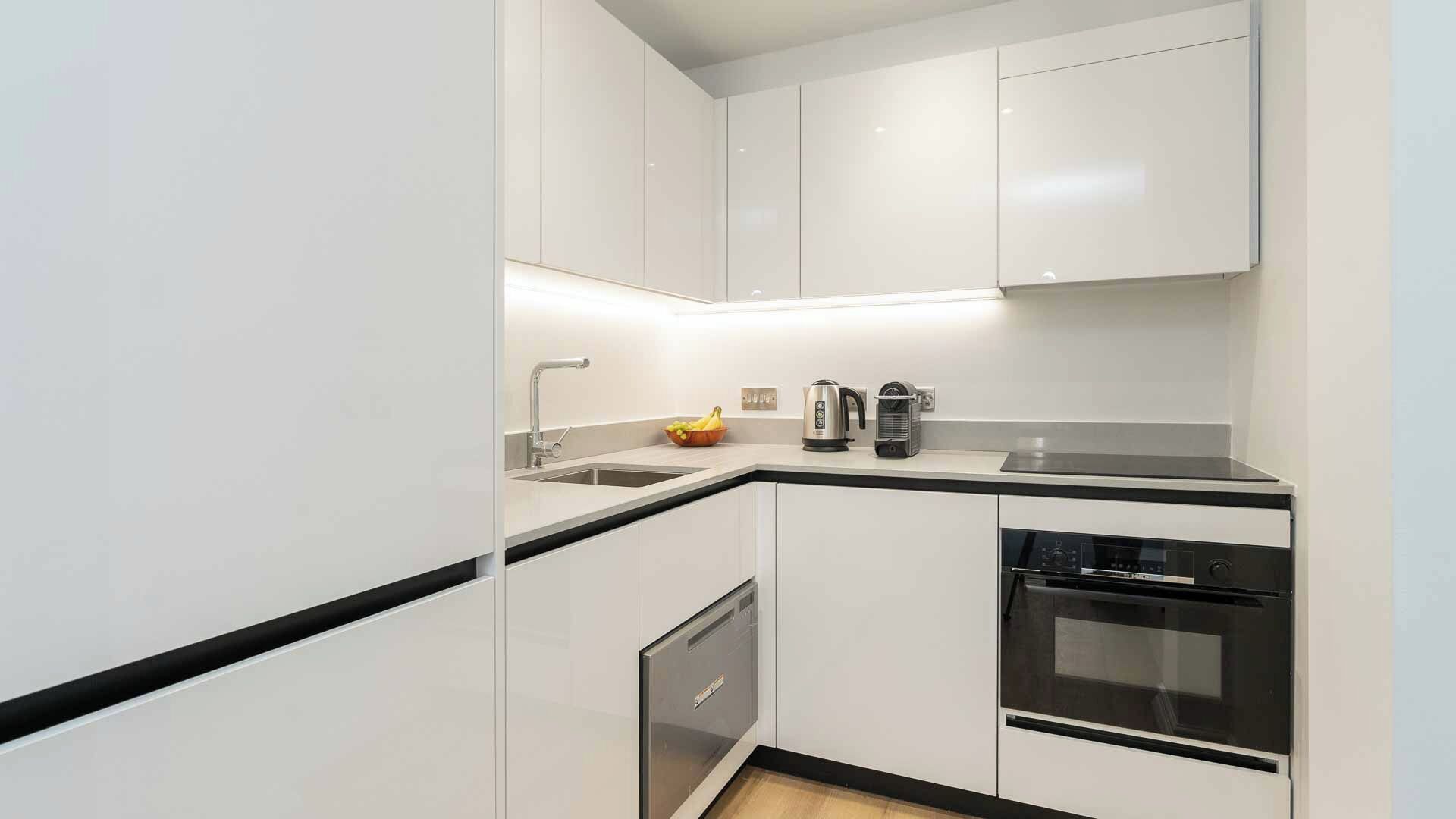 Een moderne keuken met witte kasten, een zwart aanrecht, een inbouw vaatwasser en een fornuis.
