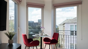 A balcony with a table and two red chairs, overlooking a cityscape. - PREMIER SUITES Edinburgh Fountain Court (Edinburgh)