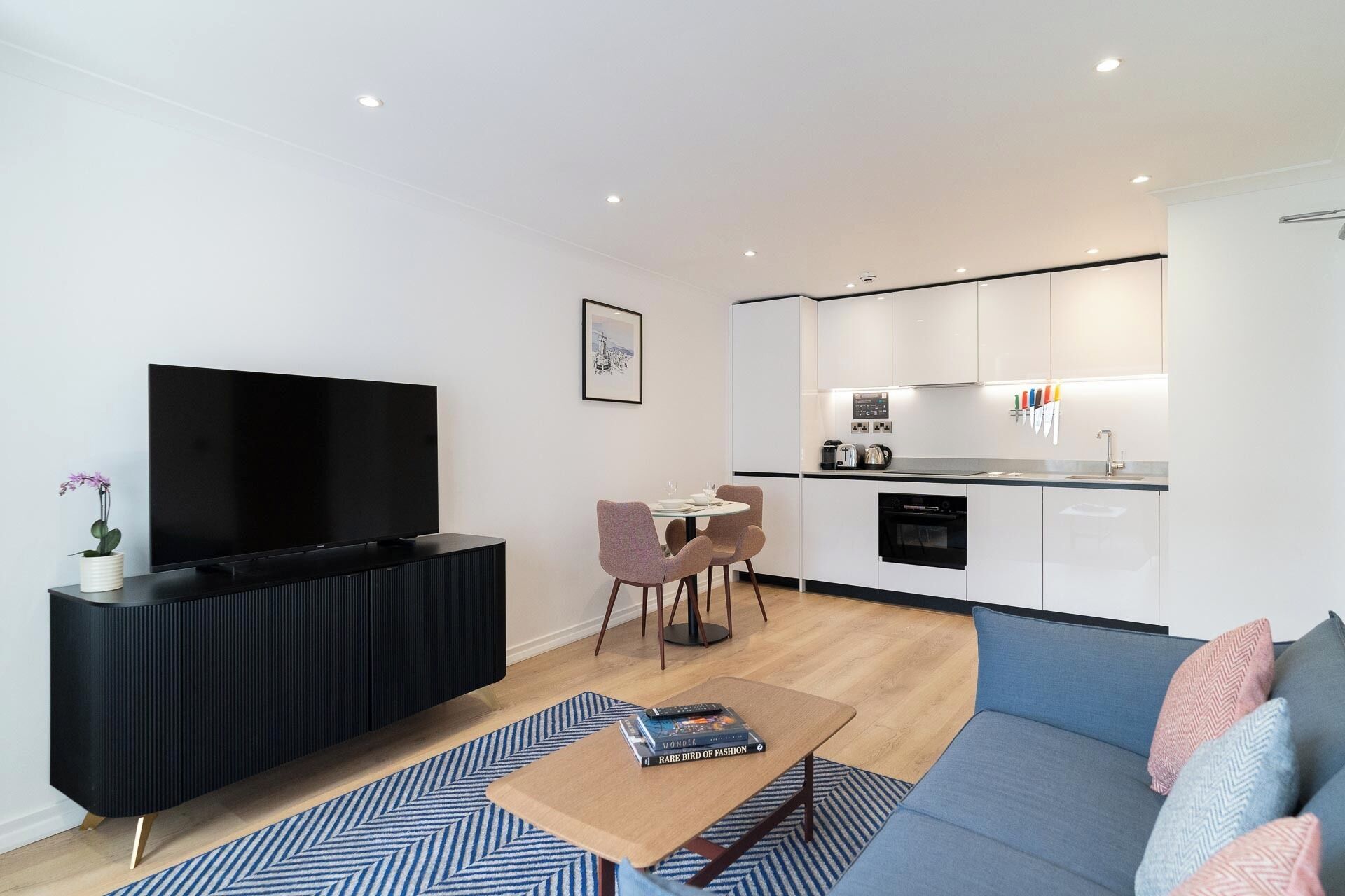 Ein modernes Wohnzimmer mit Fernseher, Couchtisch und einer gepolsterten Couch mit Kissen.
