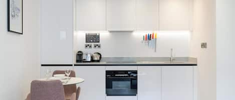 A modern kitchen with white cabinets, a black countertop, and a dining area with a table and chairs.