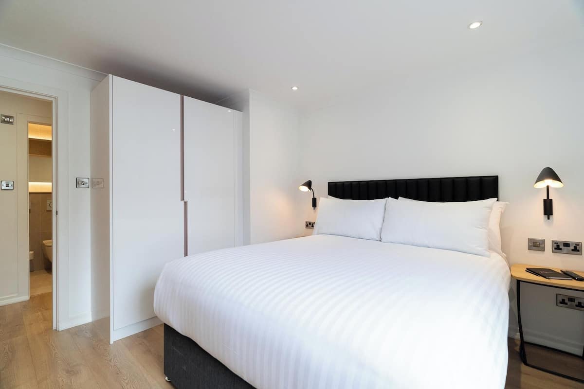 A hotel room with a large bed, a wardrobe, bedside lamps, and a nightstand.