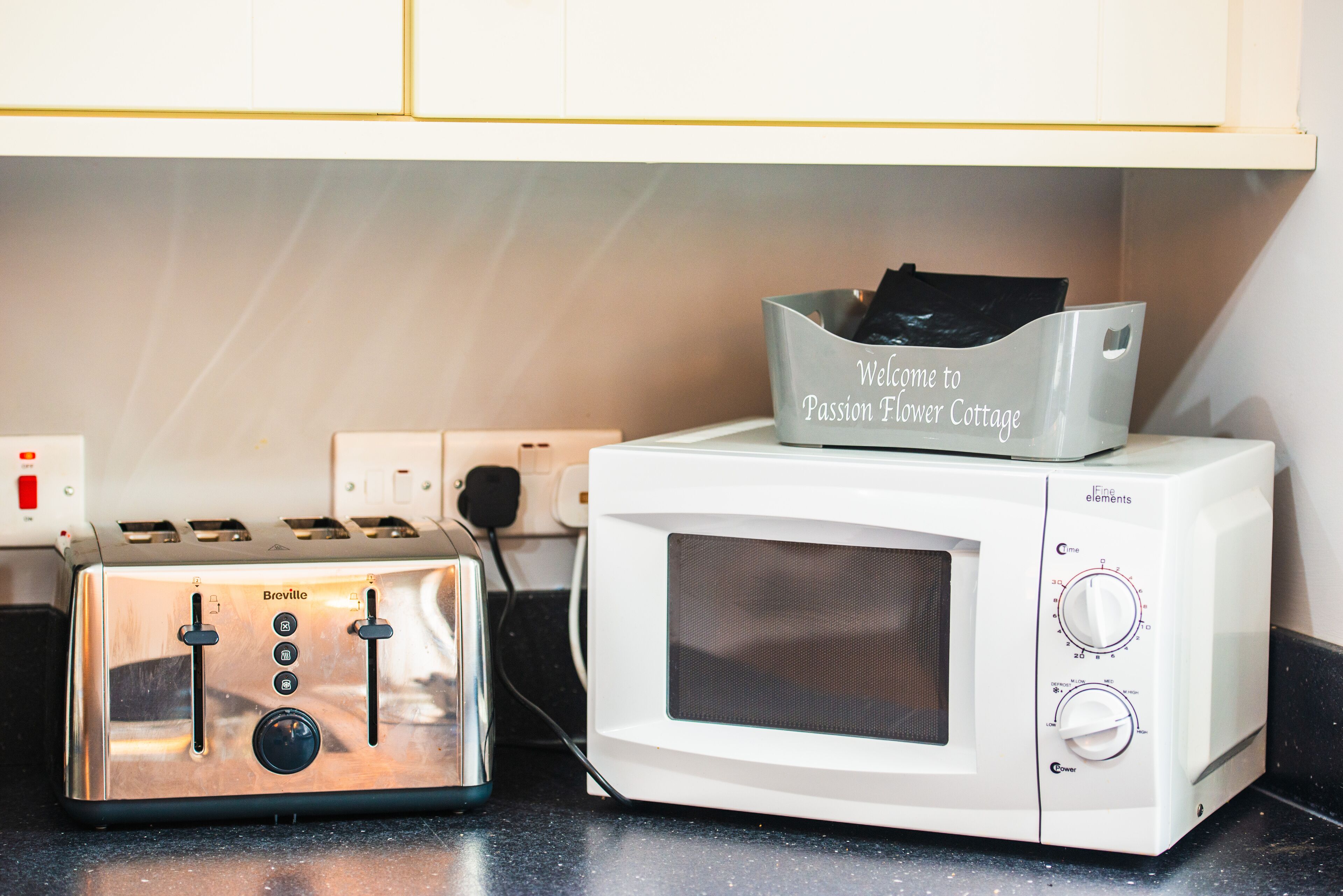 Une cuisine équipée d’un grille-pain Breville et d’un four à micro-ondes blanc.