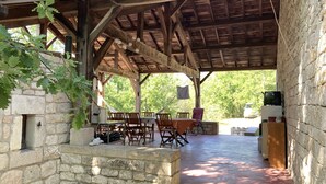 Un espacio al aire libre cubierto con paredes de piedra, muebles de madera y una mesa preparada para comer.