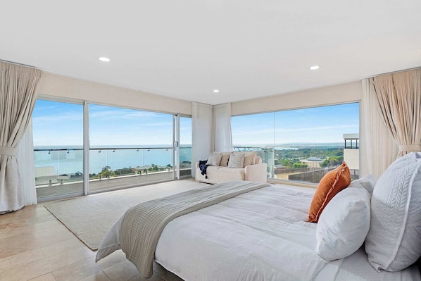 Ein Schlafzimmer mit einem großen Bett, einer Couch und einem Balkon mit Blick.