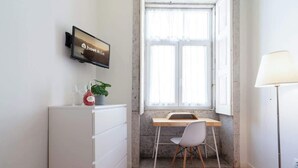 Et lille, moderne værelse med et skrivebord, stol og et fjernsyn på væggen, der viser 'hostwise'.