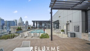 Área de piscina en la azotea con sillones, piscina y vista panorámica de la ciudad.