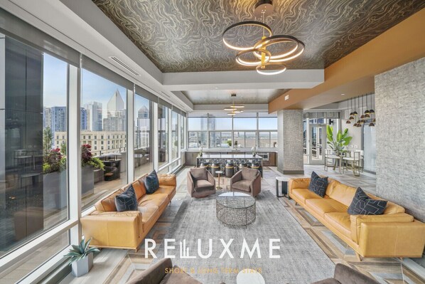 A modern interior with a high ceiling, large windows, and a seating area with sofas and a coffee table.