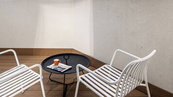 Une terrasse sur le toit, avec une table et deux chaises, d’où l’on peut admirer la vue sur les toits de la ville.