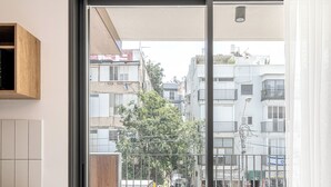 A modern apartment with a sliding glass door leading to a balcony with two red chairs and a small table. - Mate GEORGE - By HOMY (Tel Aviv)
