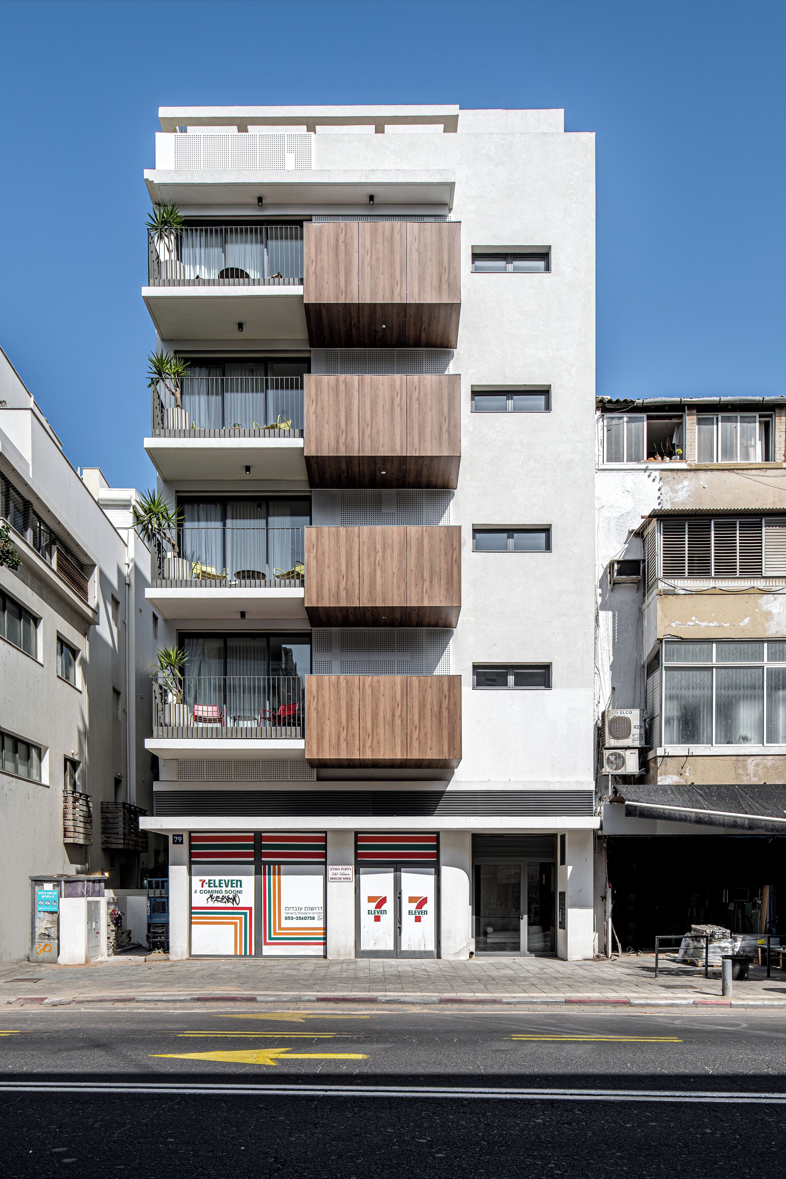Un immeuble à plusieurs étages doté de balcons, un magasin 7-Eleven et une borne d’incendie bien visible.