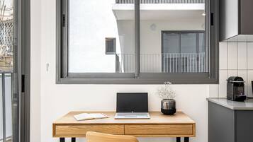 A modern kitchen with a wooden desk, a laptop, and a chair.
